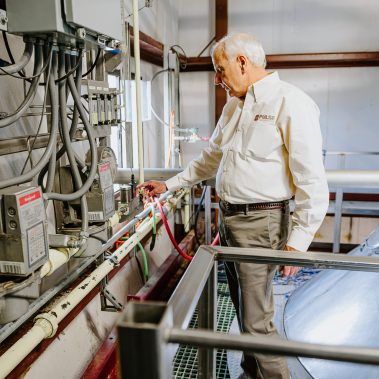 An expert engineer making precise adjustments to the control interface of an industrial spray dryer, which is a key component of a complete pulse combustion system.