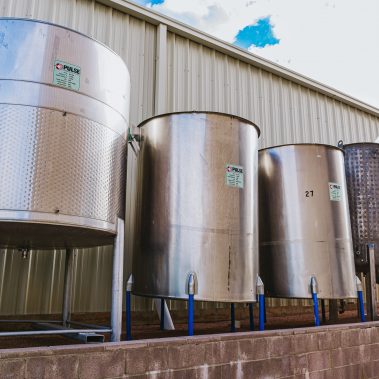 A row of gleaming stainless steel tanks, representing the high-capacity storage solutions offered by Pulse Combustion Systems for industrial drying.