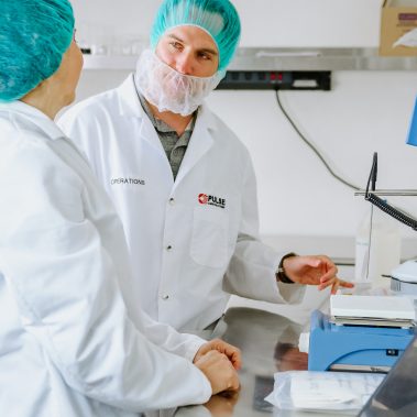 Operations team members collaborating in a lab setting, discussing data related to their advanced spray drying equipment and industrial drying solutions.