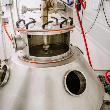 A detailed close-up of a robust spray dryer atomizer mounted on the stainless steel lid of an industrial drying chamber, central to the spray drying system.