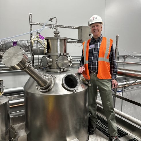 A Pulse.com expert standing proudly next to the P-50 industrial spray dryer, demonstrating the scale and robust engineering of our spray drying systems.